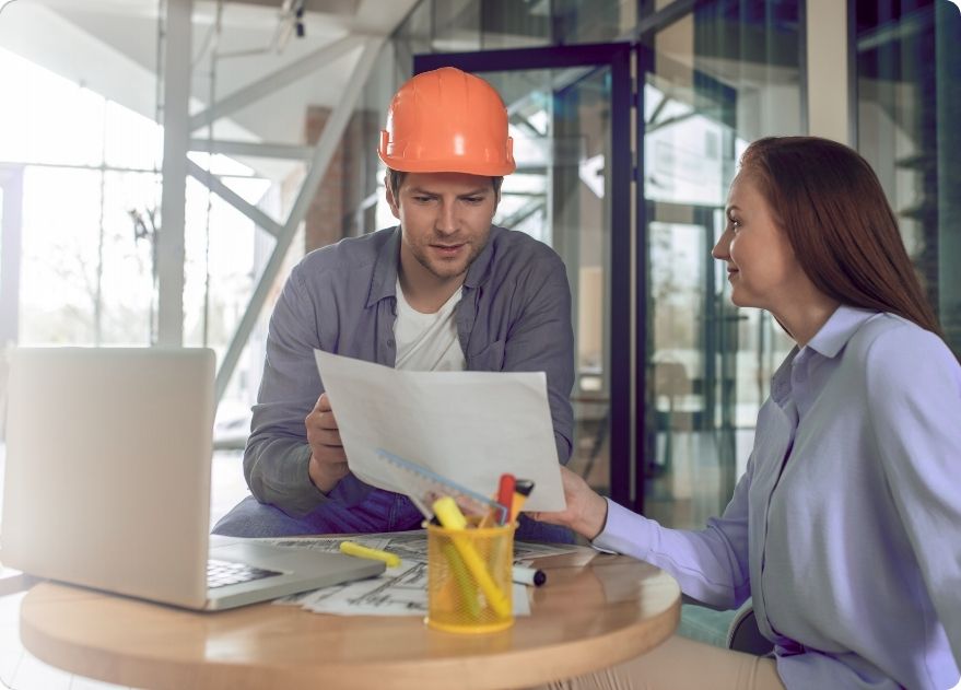 Two people discussing manufacturing in construction projects indoors.