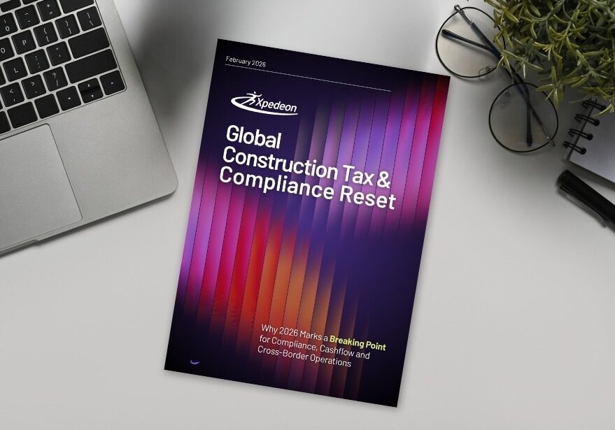 report titles construction tax and compliance reset on a desk near a laptop