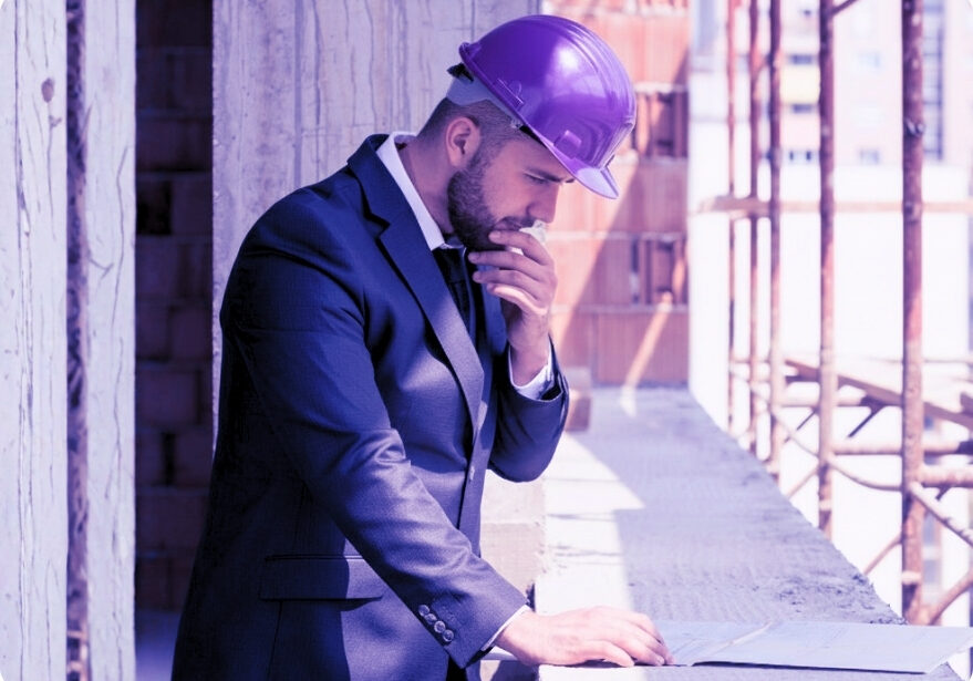 Man in suit at construction site reviewing job costing.