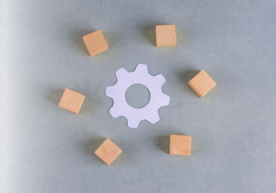 Gear surrounded by wooden cubes showing control in construction